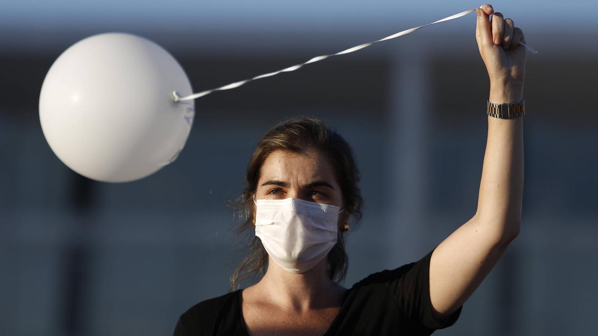 Eine Frau hält einen weißen Luftballon auf einer Corona-Gedenkveranstaltung in Brasilia, Brasilien, in die Luft Eine Frau hält einen weißen Luftballon auf einer Corona-Gedenkveranstaltung in Brasilia, Brasilien, in die Luft