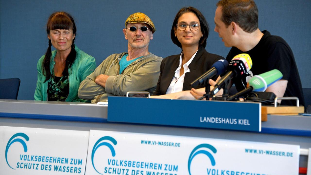 Patrick Breyer (r), Organisator, Serpil Midyatli, SPD-Landesvorsitzende, Rötger Feldmann alias Brösel, Comiczeichner, und seine Frau Petra (l) sitzen bei einer Pressekonferenz beim Start des Volksbegehrens zum Schutz des Wassers in Kiel auf dem Podium. Patrick Breyer (r), Organisator, Serpil Midyatli, SPD-Landesvorsitzende, Rötger Feldmann alias Brösel, Comiczeichner, und seine Frau Petra (l) sitzen bei einer Pressekonferenz beim Start des Volksbegehrens zum Schutz des Wassers in Kiel auf dem Podium.
