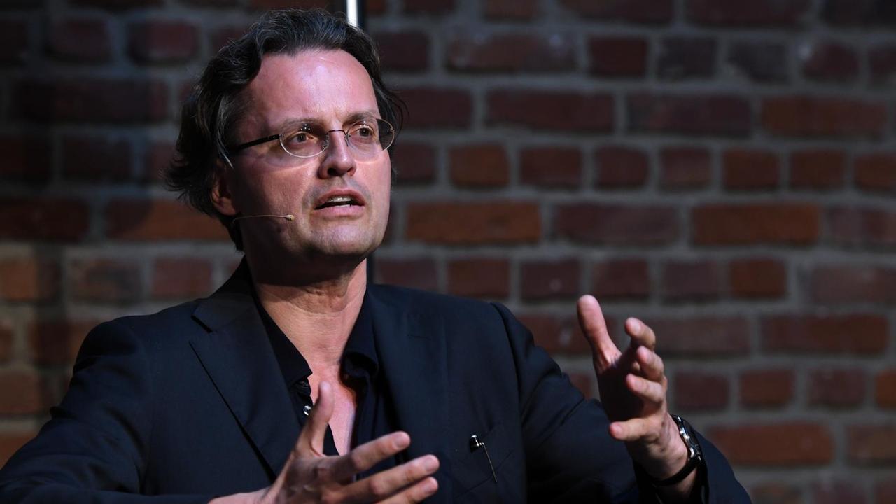 Der Medienwissenschaftler und Autor Bernhard Pörksen. Ein Mann mit dunklen, kurzen Haaren und Brille sitzt auf einem Podium und spricht.