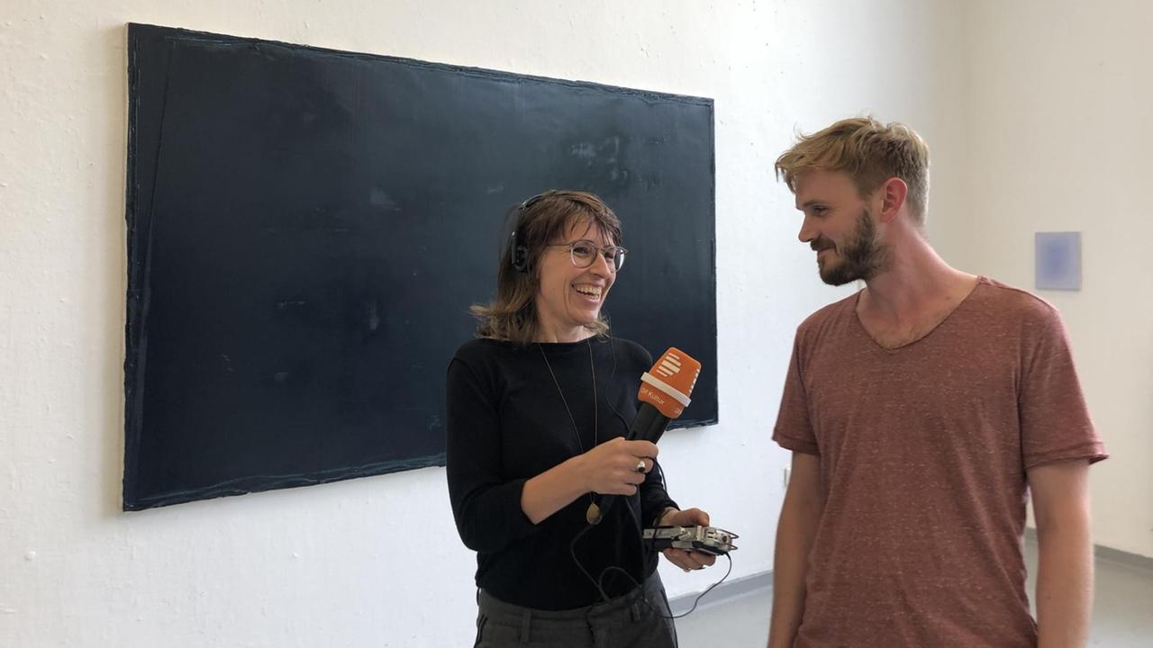 Susanne Burg mit Felix Becker vor einem Werk bei der Präsentation der künstlerischen Arbeiten.