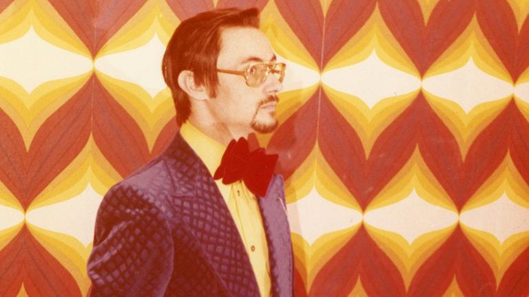Herr M. in jungen Jahren. Ein Mann steht vor einer 70er-Jahre-Tapete. Herr M. in jungen Jahren. Ein Mann steht vor einer 70er-Jahre-Tapete.