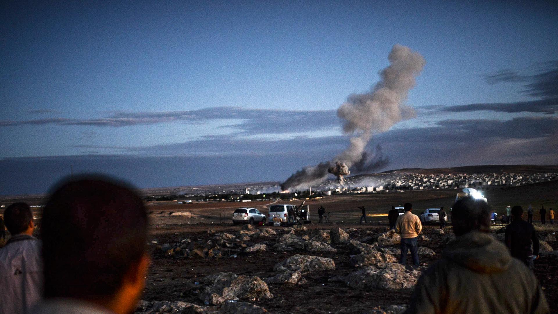 Menschen schauen aus der Ferne auf Kobane - über der Stadt sind Rauchwolken zu sehen. Menschen schauen aus der Ferne auf Kobane - über der Stadt sind Rauchwolken zu sehen.