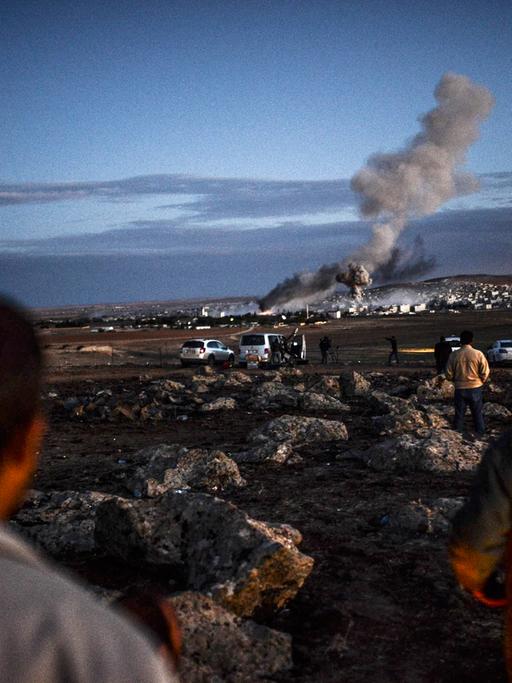 Menschen schauen aus der Ferne auf Kobane - über der Stadt sind Rauchwolken zu sehen.