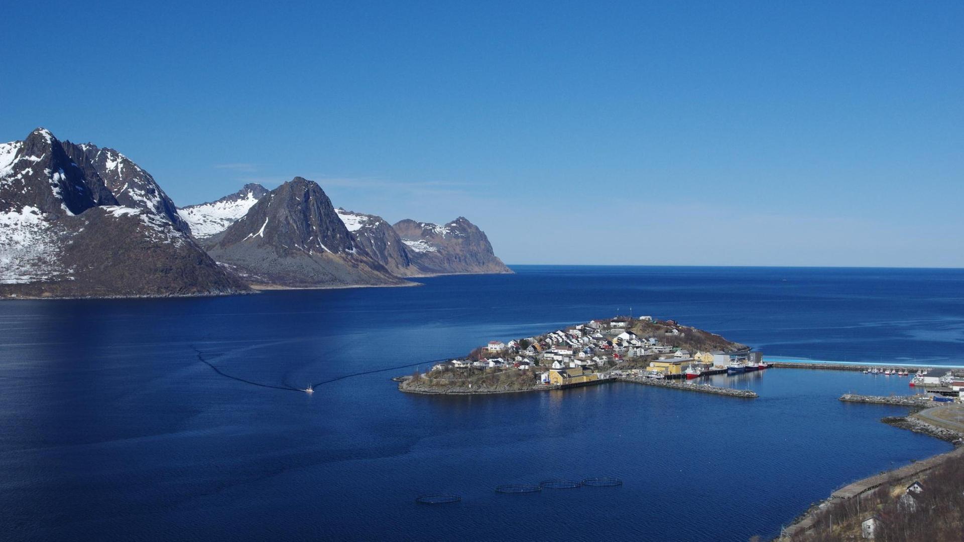 Ein auf einer Insel gelegenes Fischerdorf in Norwegen. Im Hintergrund sind Berge und der Horizont zu sehen. Ein auf einer Insel gelegenes Fischerdorf in Norwegen. Im Hintergrund sind Berge und der Horizont zu sehen.