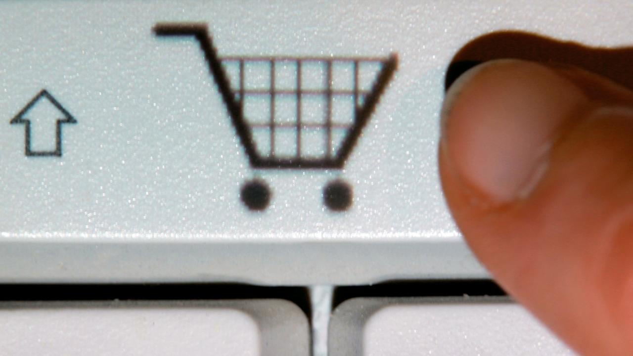 Ein Finger zeigt auf das Symbol eines Einkaufwagens auf einer Taste einer Computertastatur (gestelltes Foto). Ein Finger zeigt auf das Symbol eines Einkaufwagens auf einer Taste einer Computertastatur (gestelltes Foto).