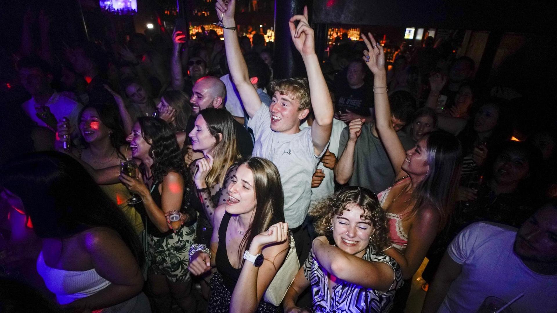 Junge Menschen feiern in einem Club. Sie tragen keine Masken und tanzen eng nebeneinander - so wie vor der Corona-Pandemie. Junge Menschen feiern in einem Club. Sie tragen keine Masken und tanzen eng nebeneinander - so wie vor der Corona-Pandemie.
