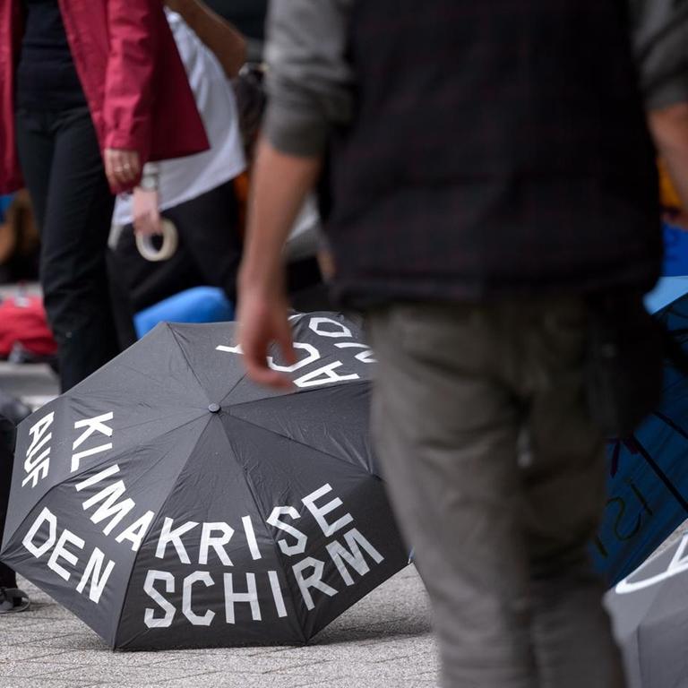 "Klimakrise auf den Schirm" steht auf dem Regenschirm der vor einer Demonstration auf dem Boden liegt. Verschiedene Ortsgruppen von Extinction Rebellion haben bei dezentralen Aktionen vor Medienhäusern unter dem Motto "Klimakrise auf die Titelseiten" zu einer besseren Berichterstattung über die Klimakrise aufgerufen