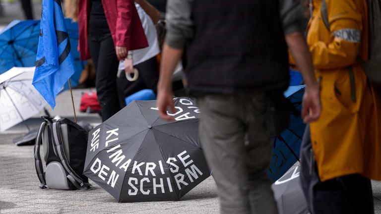 "Klimakrise auf den Schirm" steht auf dem Regenschirm der vor einer Demonstration auf dem Boden liegt. Verschiedene Ortsgruppen von Extinction Rebellion haben bei dezentralen Aktionen vor Medienhäusern unter dem Motto "Klimakrise auf die Titelseiten" zu einer besseren Berichterstattung über die Klimakrise aufgerufen