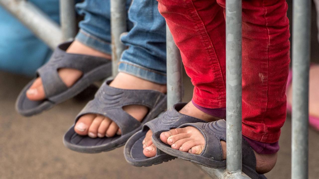 Kinder warten an einem Zaun Kinder warten an einem Zaun