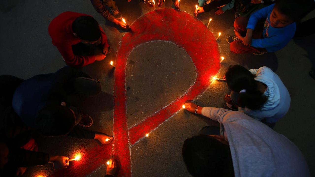 Menschen haben mit Lichter die Aids-Solidaritätsschleife gebildet Menschen haben mit Lichter die Aids-Solidaritätsschleife gebildet