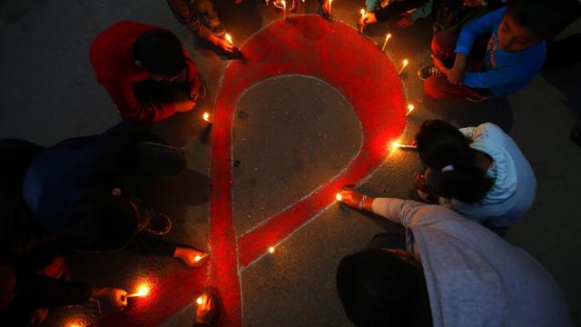 Menschen haben mit Lichter die Aids-Solidaritätsschleife gebildet