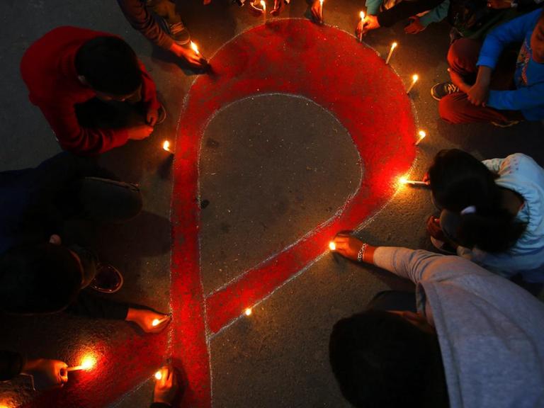 Menschen haben mit Lichter die Aids-Solidaritätsschleife gebildet
