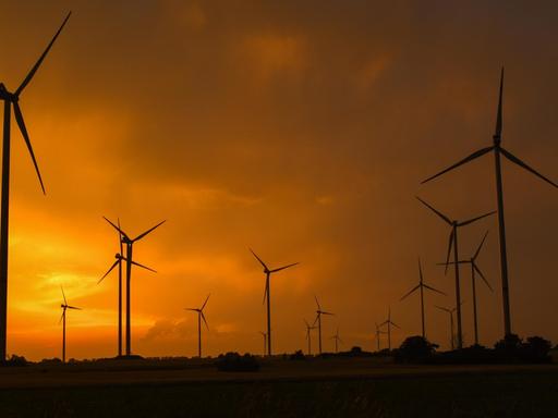 Sonnenuntergang hinter aufziehenden Gewitterwolken über der Landschaft mit Windenergieanlagen im Landkreis Oder-Spree in Ostbrandenburg