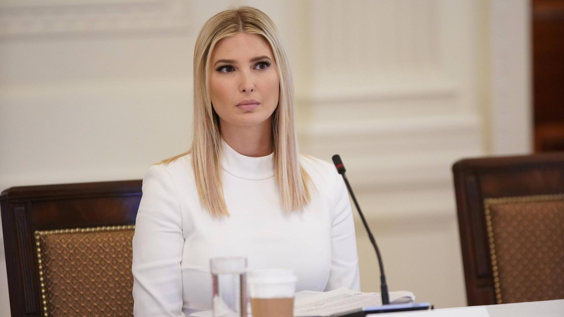 Ivanka Trump mit langen blonden Haare in weiß gekleidet sitzt vor einem Mikrofon am Tisch Ivanka Trump mit langen blonden Haare in weiß gekleidet sitzt vor einem Mikrofon am Tisch