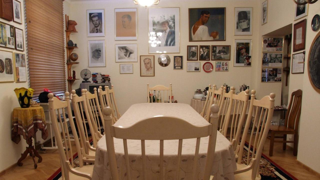 Eine Tafel mit leeren Stühlen in einem Wohnzimmer. An der Wand hängen Bilder. Eine Tafel mit leeren Stühlen in einem Wohnzimmer. An der Wand hängen Bilder.