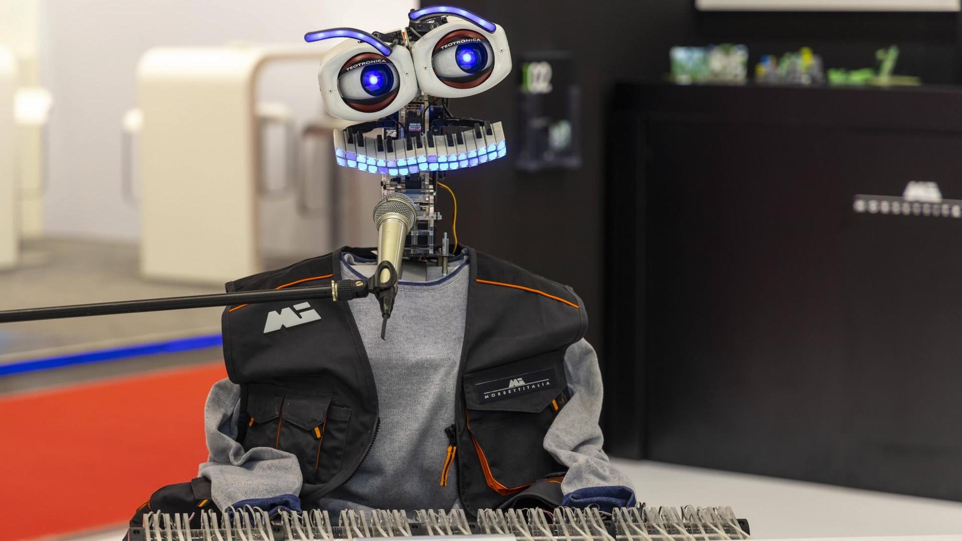 Ein Roboter mit Tastaturmund und großen Augen sitzt vor einer Klaviatur und Mikrofon und scheint zu musizieren. Ein Roboter mit Tastaturmund und großen Augen sitzt vor einer Klaviatur und Mikrofon und scheint zu musizieren.