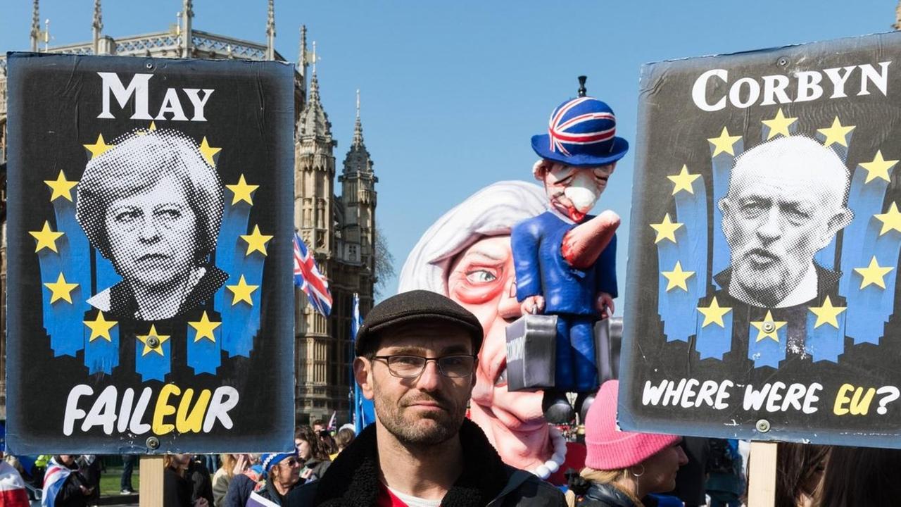 Ein Anti-Brexit-Demonstrant hält Plakate von May und Corbyn in den Händen Ein Anti-Brexit-Demonstrant hält Plakate von May und Corbyn in den Händen