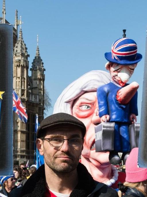 Ein Anti-Brexit-Demonstrant hält Plakate von May und Corbyn in den Händen