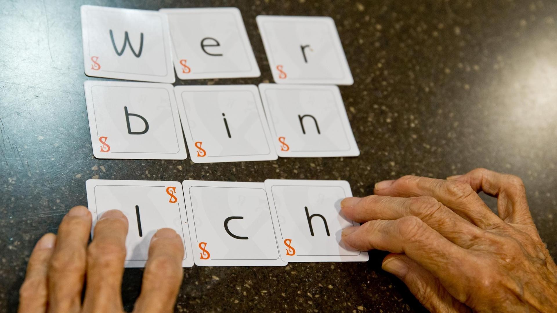 Eine Demenzkranke Frau legt die Karten eines Spiels zu dem Satz "wer bin ich" zusammen. Eine Demenzkranke Frau legt die Karten eines Spiels zu dem Satz "wer bin ich" zusammen.