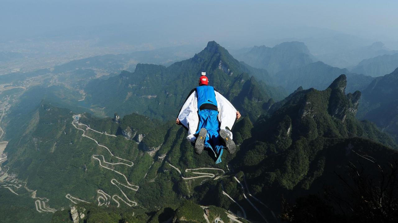 Ein Mann fliegt mit einem Wingsuit über eine chinesische Berglandschaft Ein Mann fliegt mit einem Wingsuit über eine chinesische Berglandschaft