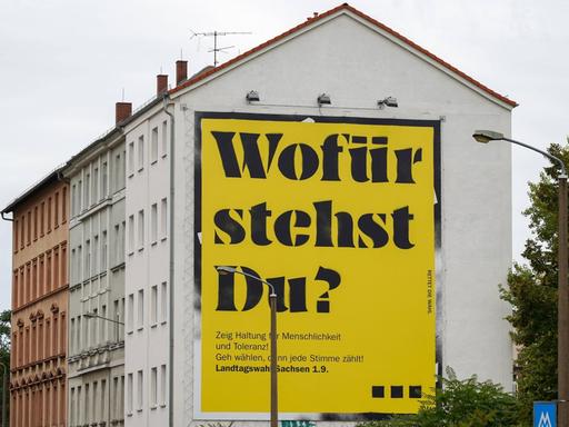 Ein Plakat mit der Aufschrift "Wofür stehst Du?" an einer Häuserwand in Leipzig.