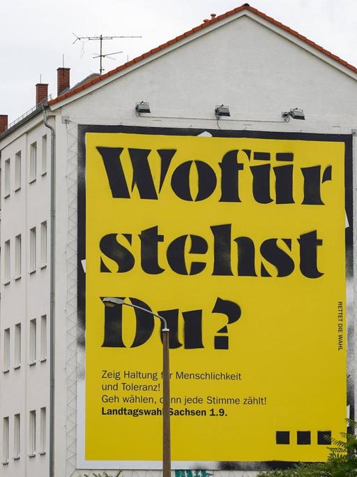 Ein Plakat mit der Aufschrift "Wofür stehst Du?" an einer Häuserwand in Leipzig.