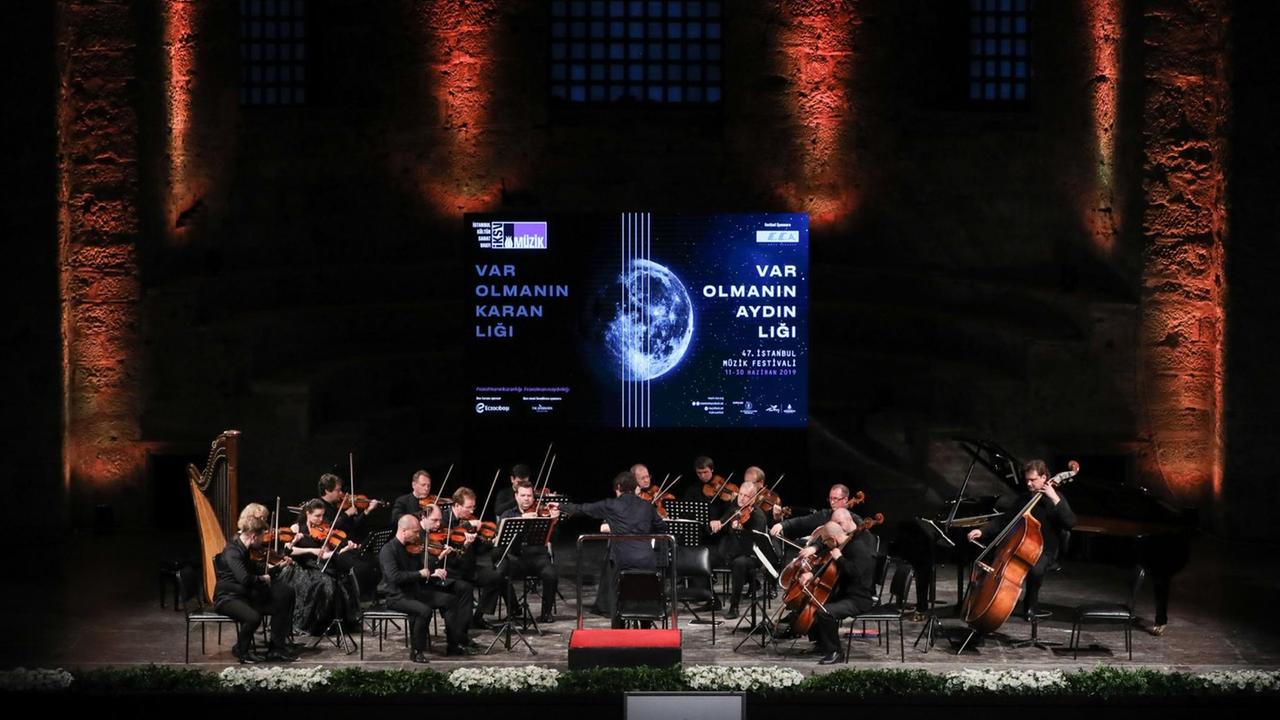 Ein Kammerorchester auf einer Bühne, die im Hintergrund das Logo das Festivals zeigt. Ein Kammerorchester auf einer Bühne, die im Hintergrund das Logo das Festivals zeigt.