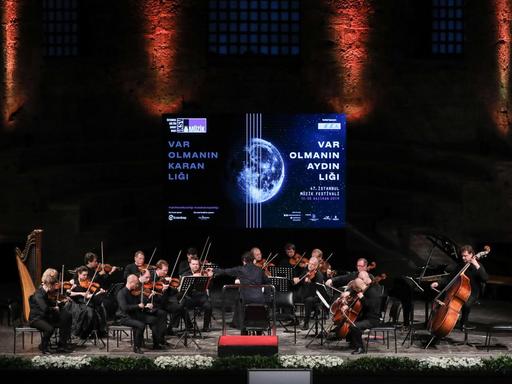 Ein Kammerorchester auf einer Bühne, die im Hintergrund das Logo das Festivals zeigt.