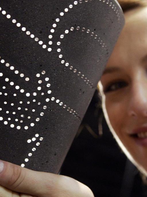 Model Andrea zeigt am Montag (11.06.2007) auf der Messe techtextil in Frankfurt/Main ein Stück lichtdurchlässigen Beton, den die technische Universität Dresden entwickelt hat.