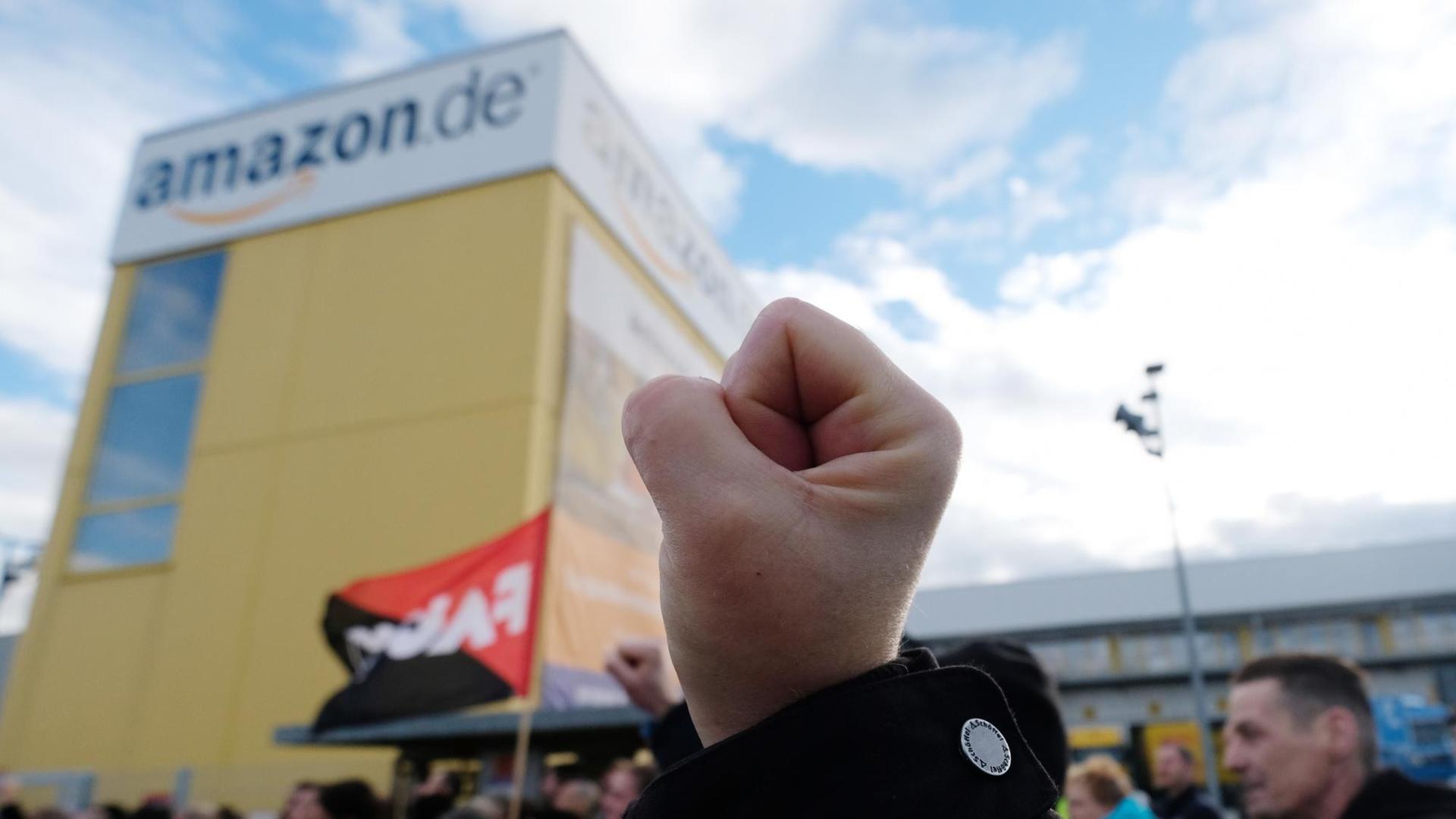 Streik bei Amazon: Ein Teilnehmer einer Kundgebung hat am 24.11.2017 in Leipzig (Sachsen) vor dem dortigen Standort des Online-Versandhandels Amazon die Faust geballt. Die Gewerkschaft Verdi hat am Freitag die Mitarbeiter mehrerer Amazon-Standorte in Deutschland zum Streik aufgerufen. Der Ausstand fällt auf den Rabatt-Tag "Black-Friday", an dem Einzelhändler bundesweit mit günstigen Angeboten locken. Streik bei Amazon: Ein Teilnehmer einer Kundgebung hat am 24.11.2017 in Leipzig (Sachsen) vor dem dortigen Standort des Online-Versandhandels Amazon die Faust geballt. Die Gewerkschaft Verdi hat am Freitag die Mitarbeiter mehrerer Amazon-Standorte in Deutschland zum Streik aufgerufen. Der Ausstand fällt auf den Rabatt-Tag "Black-Friday", an dem Einzelhändler bundesweit mit günstigen Angeboten locken.