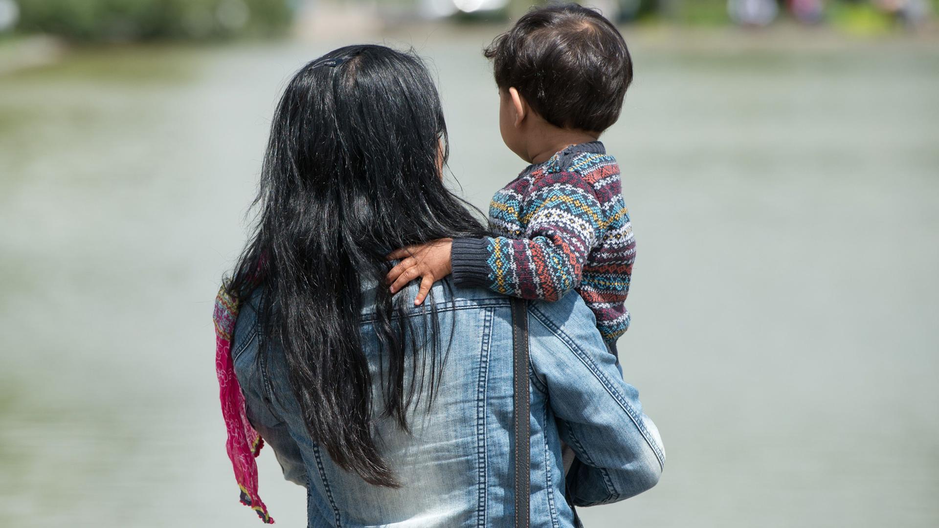 Eine Frau steht im Stuttgarter Schlossgarten und hält ein Kind auf ihrem Arm. Eine Frau steht im Stuttgarter Schlossgarten und hält ein Kind auf ihrem Arm.