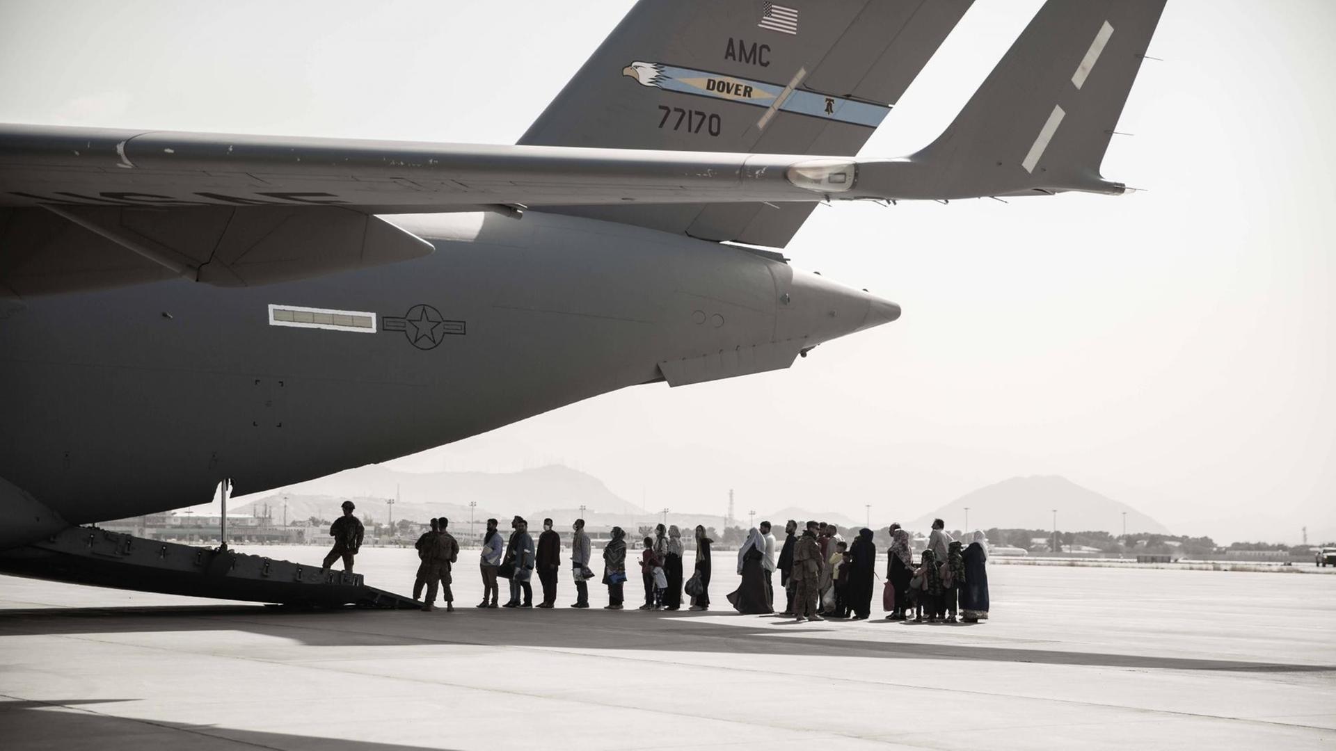 Auf dem Flugfeld des Flughafens Kabul stehen Menschen vor einem Evakuierungsflugzeug Schlange. Auf dem Flugfeld des Flughafens Kabul stehen Menschen vor einem Evakuierungsflugzeug Schlange.