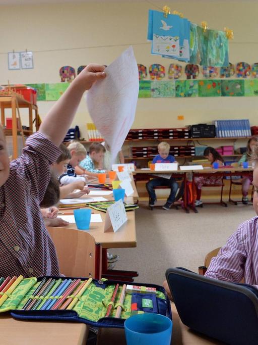 Der Junge Kilian mit Down-Syndrom hält an seinem ersten Schultag in der Grundschule Bennigsen in Springe bei Hannover ein selbstgemaltes Bild in die Höhe.