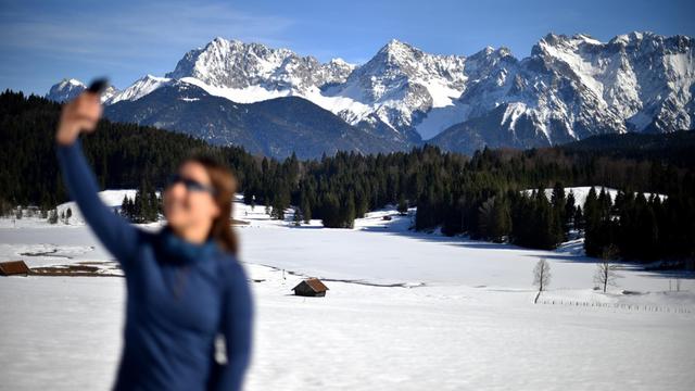 Eine Frau fotografiert sich selbst vor dem Karwendel-Gebirge (Selfie).