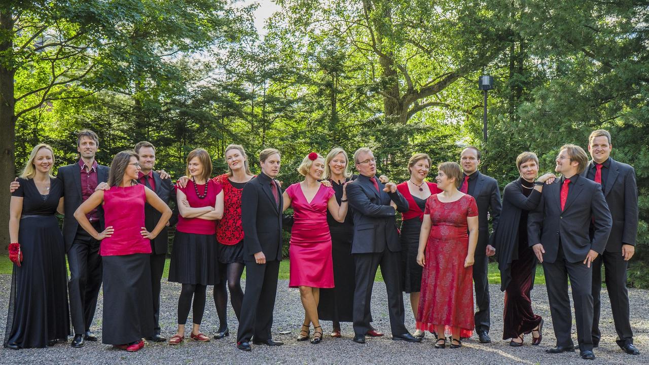 Der "Utopia"-Kammerchor steht festlich gekleidet in einem Park. Der "Utopia"-Kammerchor steht festlich gekleidet in einem Park.