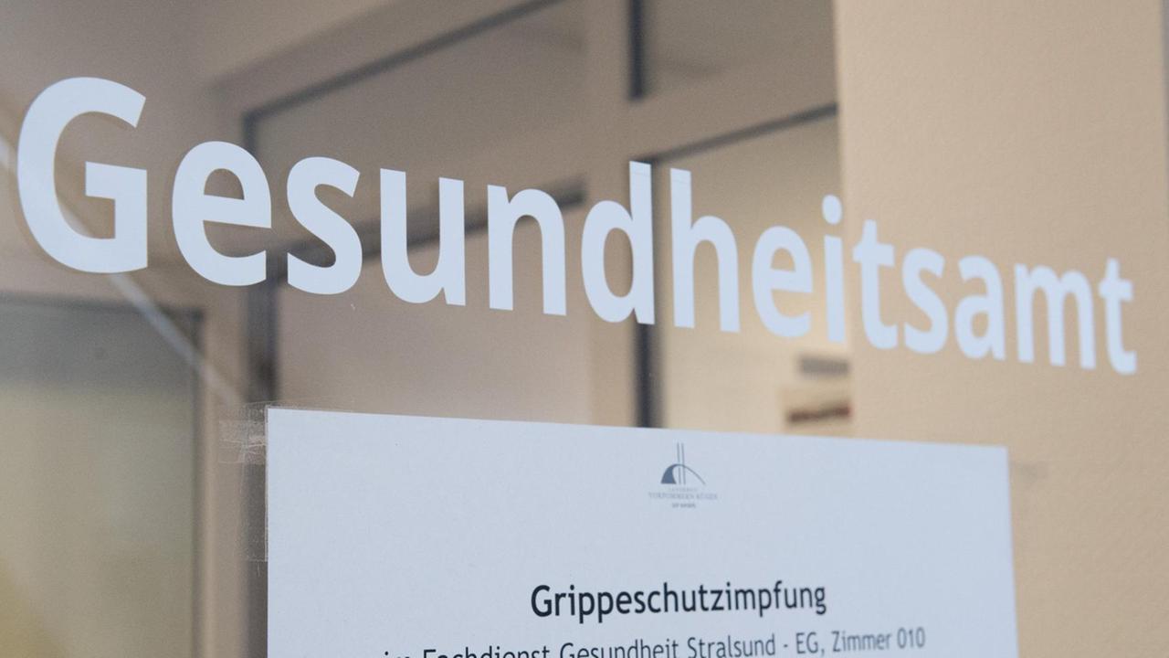Ein Hinweis auf die Grippeschutzimpfung hängt am Gesundheitsamt an der Tür. Ein Hinweis auf die Grippeschutzimpfung hängt am Gesundheitsamt an der Tür.