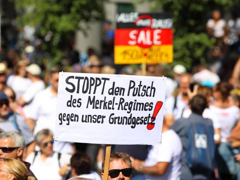 Ohne Maske und mit Anti-Merkel-Transparent demonstrieren Menschen in Berlin gegen die Anti-Corona-Maßnahmen.