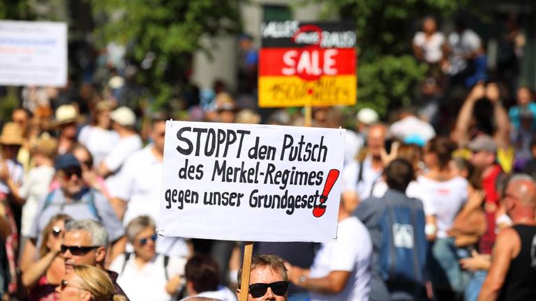 Ohne Maske und mit Anti-Merkel-Transparent demonstrieren Menschen in Berlin gegen die Anti-Corona-Maßnahmen.