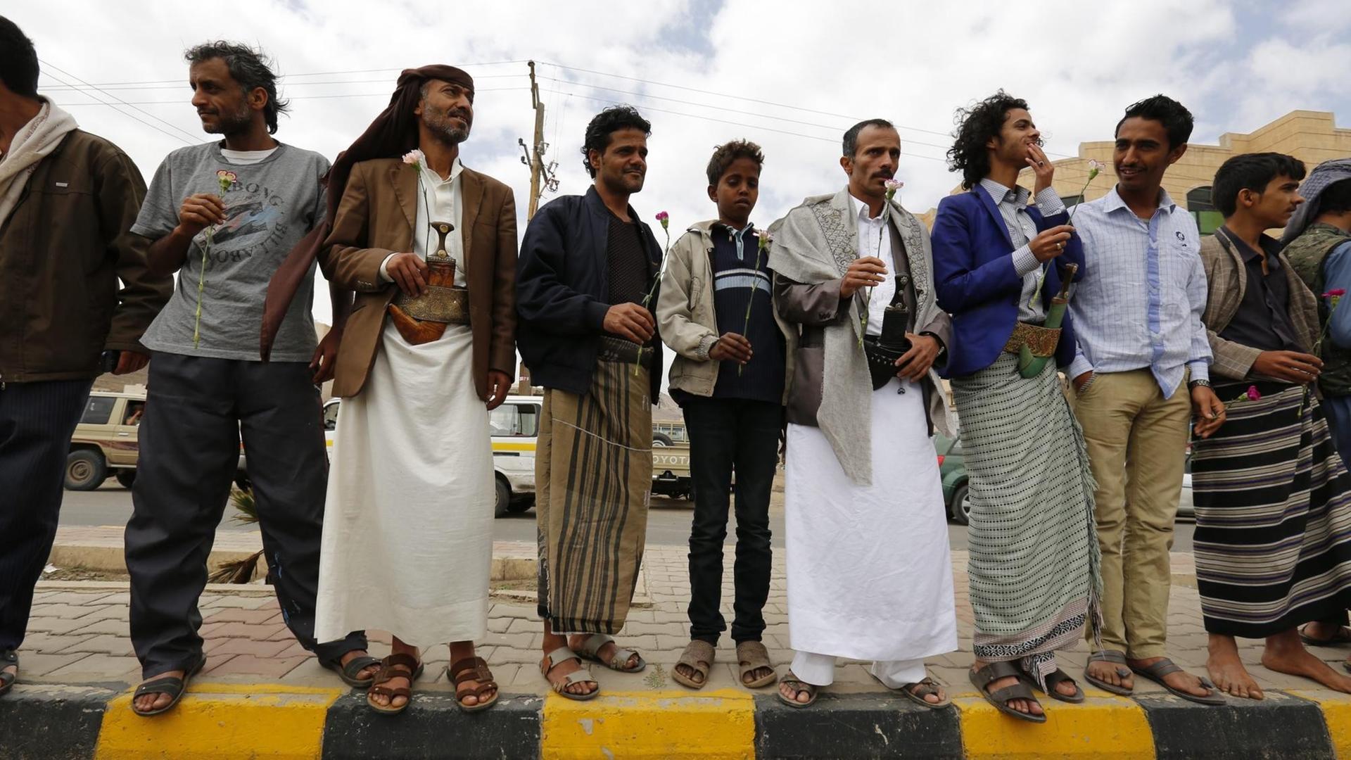 Das Bild zeigt jemenitische Bahá'í, die im April 2016 mit Blumen in den Händen vor dem Gericht in Sanaa gegen den Prozess gegen Hamed bin Haydara protestieren