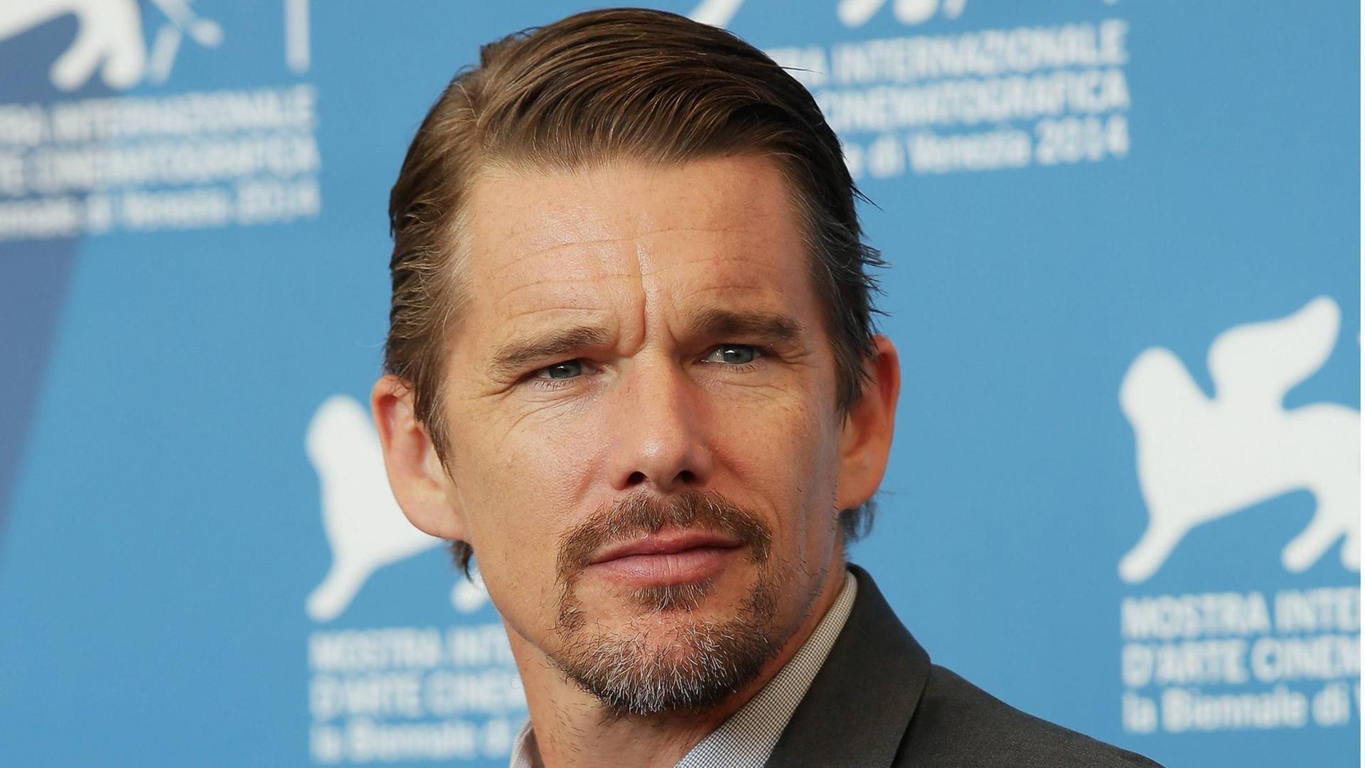 Ethan Hawke bei der Vorstellung von "Good Kill" in Venedig: Porträt von Ethan Hawke im Anzug vor hellblauer Wand. Ethan Hawke bei der Vorstellung von "Good Kill" in Venedig: Porträt von Ethan Hawke im Anzug vor hellblauer Wand.