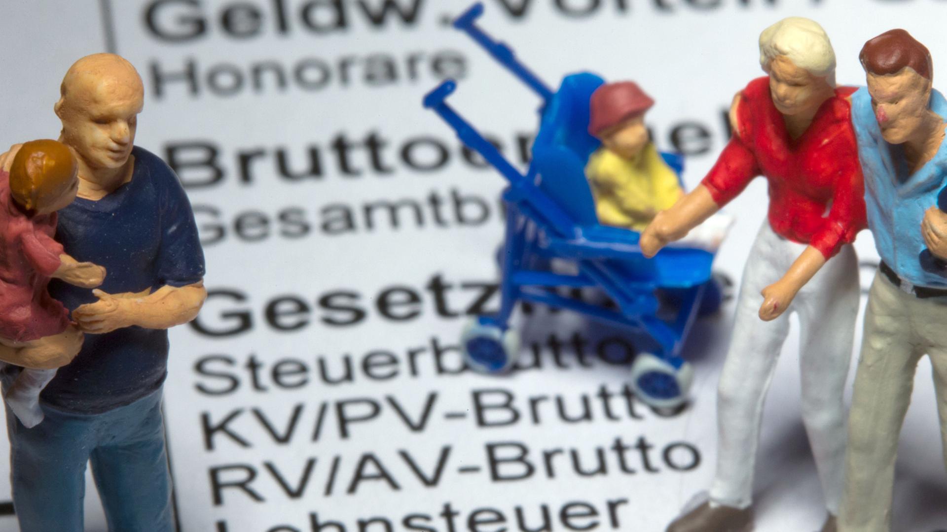 Modellfiguren stehen am 26.03.2014 in Schwerin (Mecklenburg-Vorpommern) auf einer Gehaltsabrechnung mit den Angaben zu Krankenversicherungsbeiträgen.