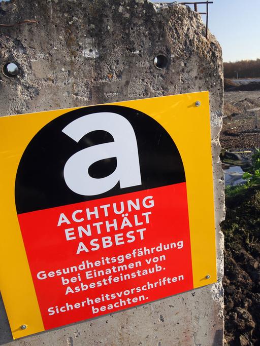 Ein Warnschild informiert über Asbest in einem Betonpfeiler