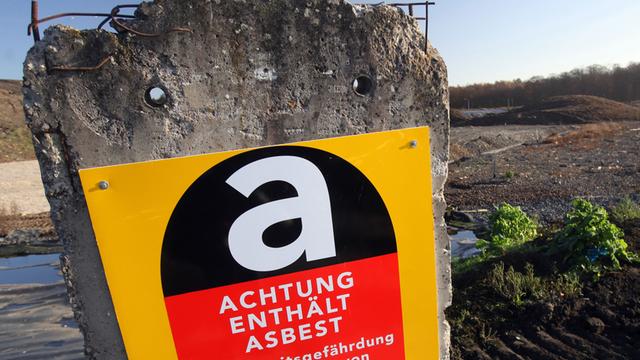 Ein Warnschild informiert über Asbest in einem Betonpfeiler