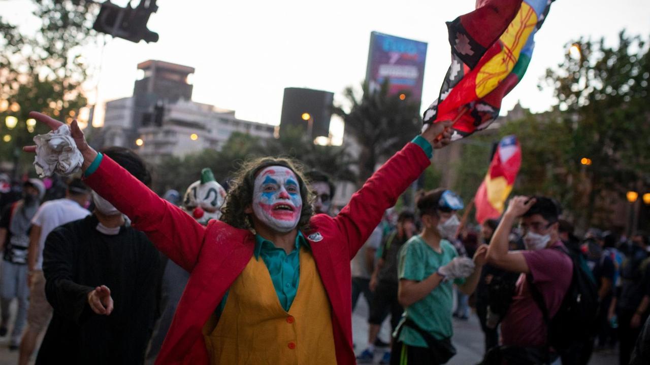 Protest in Santiago de Chile am 2. November 2019. Ein Mann mit Joker-Maske protestiert mit anderen auf einer Straße. Protest in Santiago de Chile am 2. November 2019. Ein Mann mit Joker-Maske protestiert mit anderen auf einer Straße.