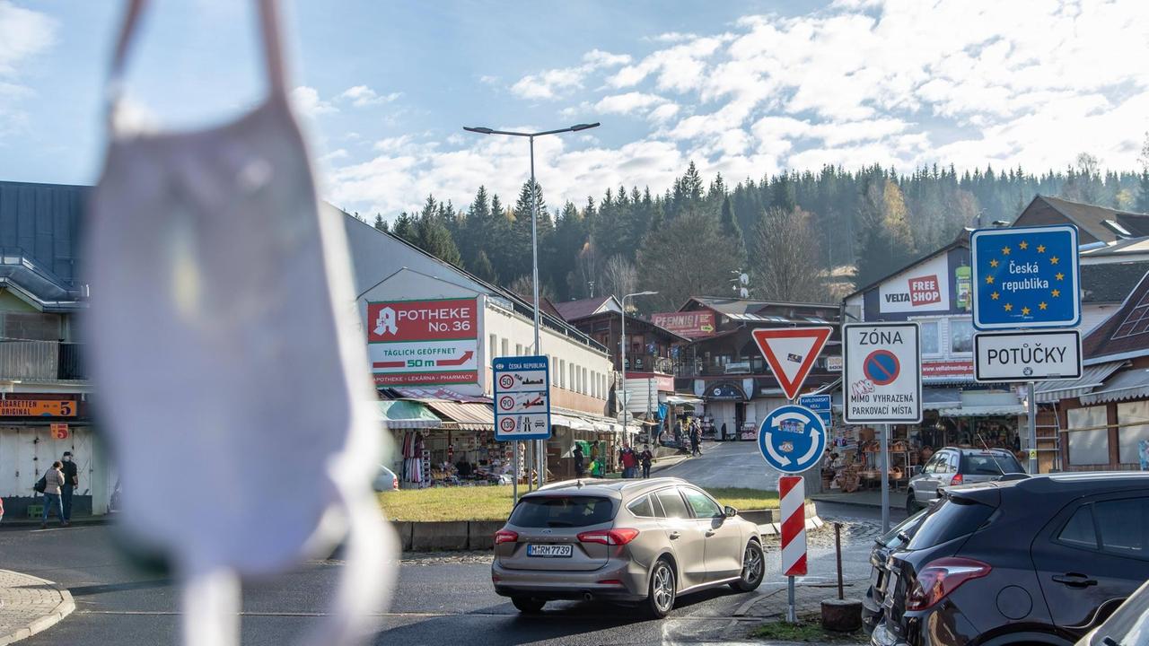 Blick auf einen Ort an der deutsch-tschechischen Grenze. Im Vordergrund ist eine Maske zu erkennen. Blick auf einen Ort an der deutsch-tschechischen Grenze. Im Vordergrund ist eine Maske zu erkennen.