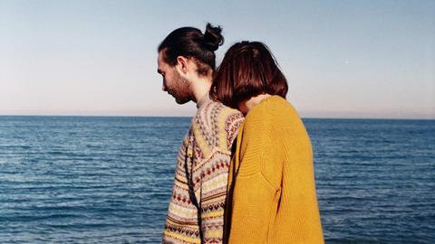 Mann und Frau in bunten Pullovern am Meer