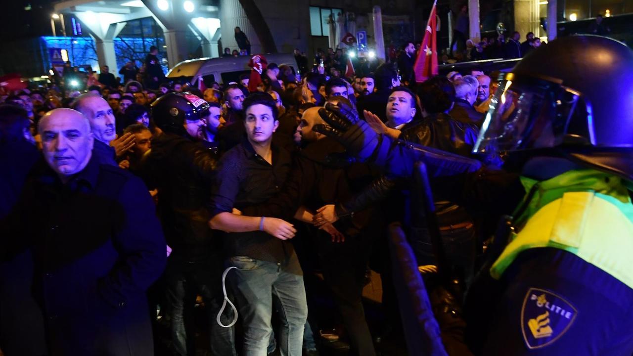 Ein Polizist neben Demonstranten in Demonstranten in Rotterdam