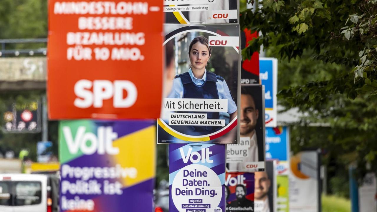Viele bunte Wahl-Plakate von verschiedenen Parteien hängen neben einer Straße an Laternen. Viele bunte Wahl-Plakate von verschiedenen Parteien hängen neben einer Straße an Laternen.