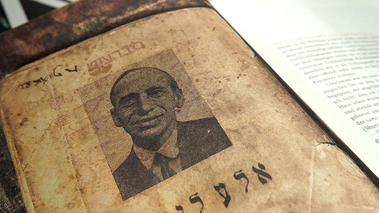 Blick auf eine Seite des Buches "Es brennt. Mordechai Gebirtig, Vater des jiddischen Liedes", darauf ein Bild von Gebirtig Blick auf eine Seite des Buches "Es brennt. Mordechai Gebirtig, Vater des jiddischen Liedes", darauf ein Bild von Gebirtig