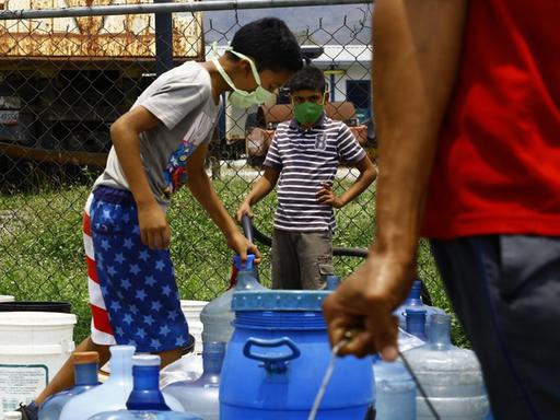 Menschen füllen Wasserkanister in Naguanagua, Venezuela.